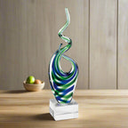 Glass sculpture with blue and green swirls on a white background